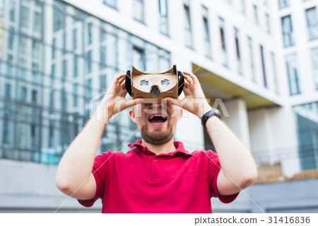 Funny man using cardboard virtual reality goggle Funny man using cardboard virtual reality goggle 31416836