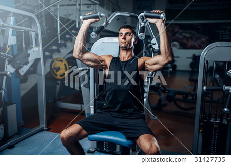 Tanned man training on exercise machine 31427735