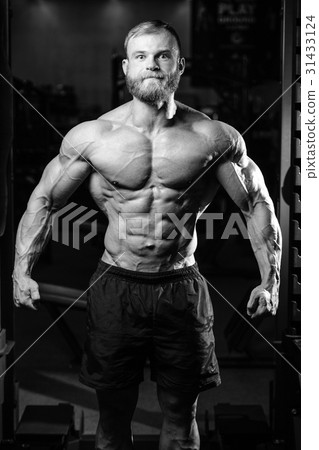 Handsome fit caucasian muscular man flexing his muscles in gym Handsome fit caucasian muscular man flexing his muscles in gym 31433124