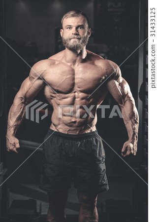 Handsome fit caucasian muscular man flexing his muscles in gym Handsome fit caucasian muscular man flexing his muscles in gym 31433125
