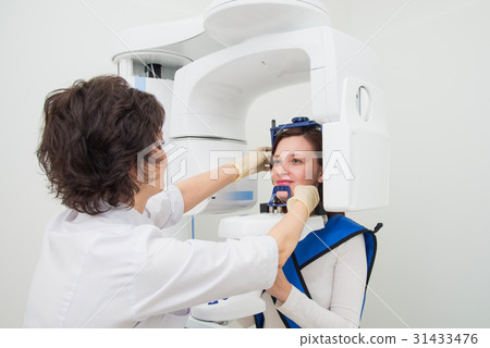 Dentist taking a panoramic digital X-ray of a Dentist taking a panoramic digital X-ray of a 31433476