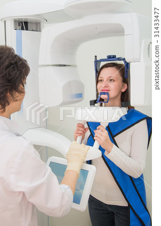 Dentist taking a panoramic digital X-ray of a Dentist taking a panoramic digital X-ray of a 31433477