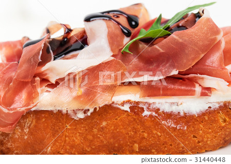 Prosciutto bruschetta with ricotta and arugula. 31440448