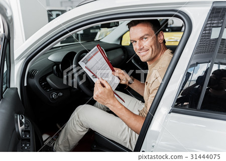 Cheerful male looking through instruction about Cheerful male looking through instruction about 31444075