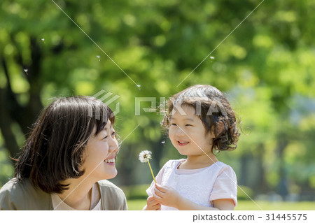 A girl and a mother playing with a dandelion in a fresh green park 31445575