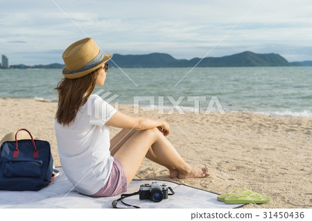 Female Traveler sitting on beach Female Traveler sitting on beach 31450436