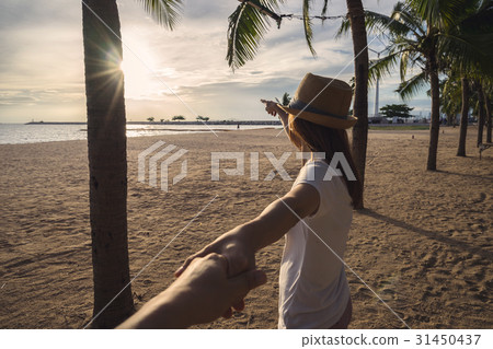young woman holding man's hand on the beach young woman holding man's hand on the beach 31450437