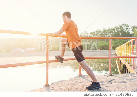 Fitness man stretching his leg muscles outdoors. Fitness man stretching his leg muscles outdoors. 31450683