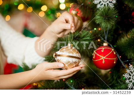 woman in sweater decorating Christmas tree woman in sweater decorating Christmas tree 31452239
