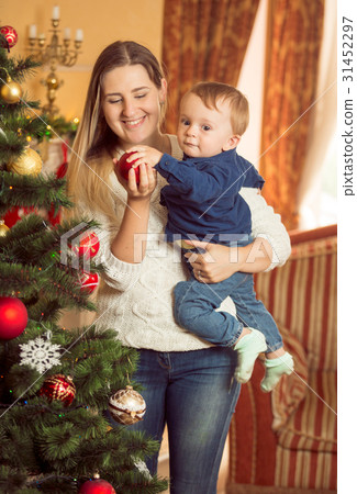 woman with her baby son decorating Christmas tree woman with her baby son decorating Christmas tree 31452297