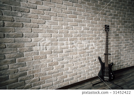 The guitar stands near the stone wall 31452422