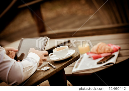 Young Man Eating Breakfast Whilst Using Tablet 31460442