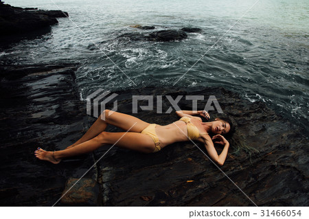 Sexy young woman lies on a rock ocean shore Sexy young woman lies on a rock ocean shore 31466054