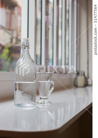 Glass of water with a bottle on table Glass of water with a bottle on table 31477564