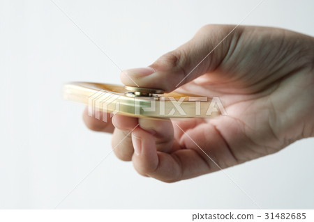 Isolated hand spinning golden metal fidget spinner Isolated hand spinning golden metal fidget spinner 31482685