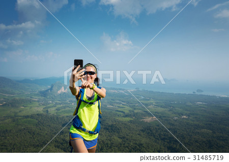 hiker taking photo with cellphone on mountain peak 31485719
