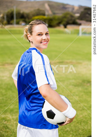Portrait of happy female football player standing with a ball 31487662