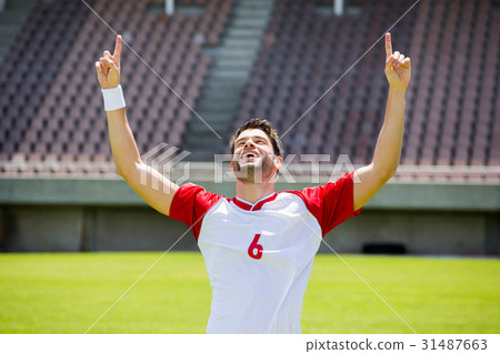 Excited football player with hands raised 31487663