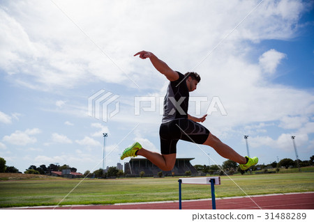 Athlete jumping above the hurdle 31488289