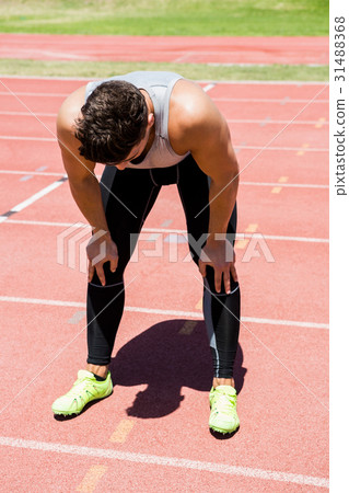 Tired athlete standing on running track 31488368