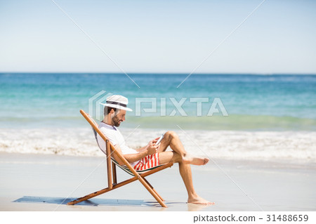 Man sitting on armchair at beach Man sitting on armchair at beach 31488659
