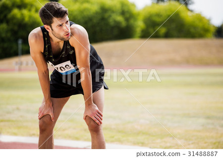Tired athlete standing on running track Tired athlete standing on running track 31488887