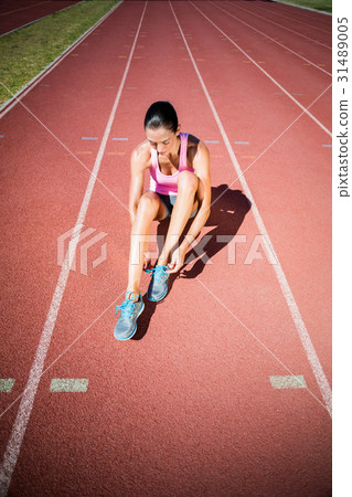 Female athlete tying her running shoes Female athlete tying her running shoes 31489005