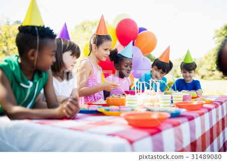 Group of children are around a table during a birthday party 31489080
