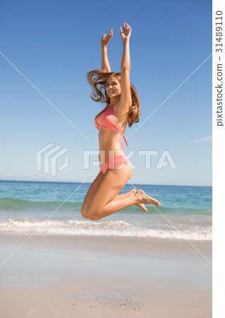 Young woman jumping on beach Young woman jumping on beach 31489110
