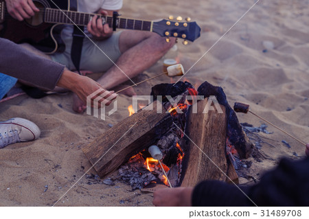 friends sitting on stones on beach. man is playing friends sitting on stones on beach. man is playing 31489708