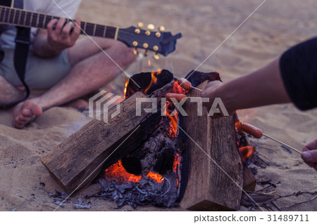 friends sitting on stones on beach. man is playing friends sitting on stones on beach. man is playing 31489711