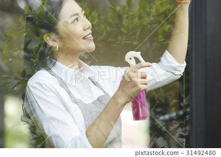 a young woman is doing housework of cleaning glass window. a young woman is doing housework of cleaning glass window. 31492480