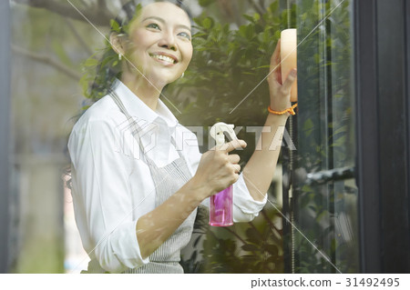 a woman is smiling, cleaning glass window and looking 31492495