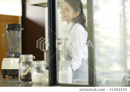 young asian lady is smiling and cooking in modern kitchen young asian lady is smiling and cooking in modern kitchen 31492559