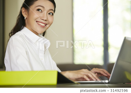 a businesswoman is smiling and working on the laptop. a businesswoman is smiling and working on the laptop. 31492596