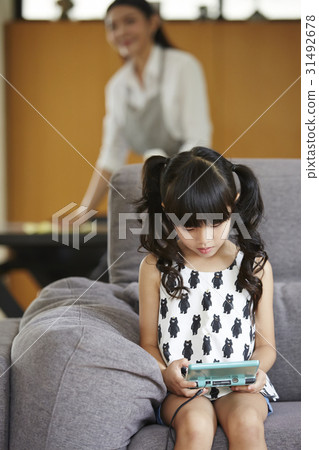 a little girl is sitting and playing handheld video game. a little girl is sitting and playing handheld video game. 31492678