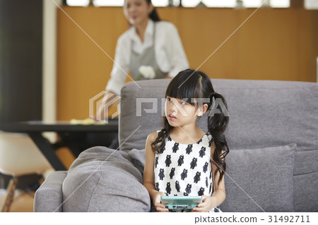 A photo of cute little girl sitting on the sofa at home. A photo of cute little girl sitting on the sofa at home. 31492711