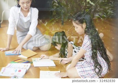 Mom teaches daughters to draw and do homework on floor 31492830