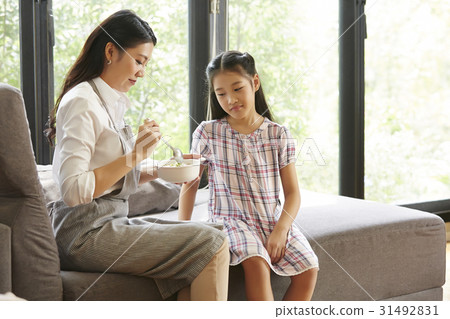 Mother is feeding her daughter on sofa 31492831