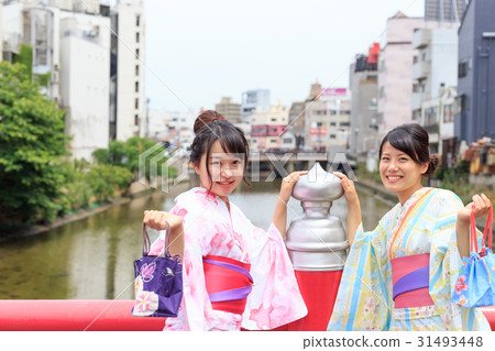 Summer image Young lady in a yukata fun enjoying at the railing of a red bridge 31493448