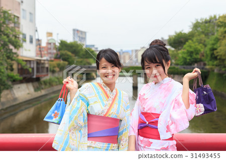 Summer image Young lady in a yukata fun enjoying at the railing of a red bridge 31493455