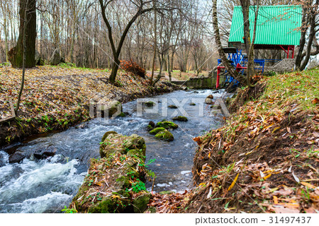 Metallic wheel watermill in a park Metallic wheel watermill in a park 31497437