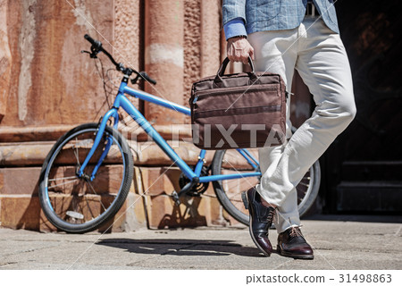 Stylish male person keeping bad near bike Stylish male person keeping bad near bike 31498863