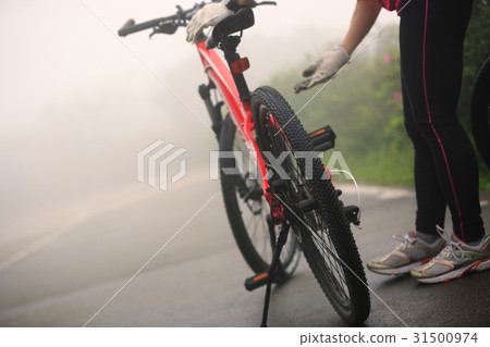 cyclist fix the bike chain on foggy road 31500974