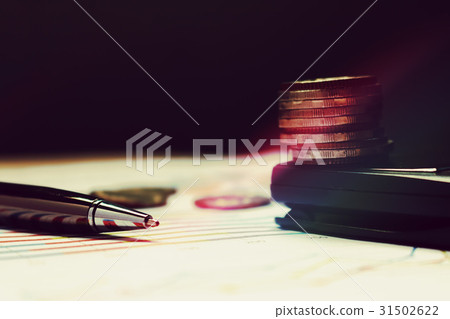 Pen on summary report and coin on calculator. 31502622