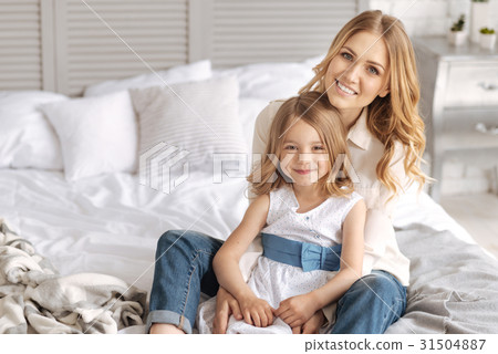 Happy smiling mother and daughter hugging on bed Happy smiling mother and daughter hugging on bed 31504887