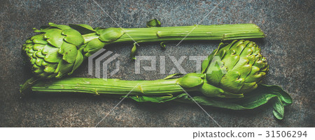 Fresh raw green artichockes over dark stone Fresh raw green artichockes over dark stone 31506294