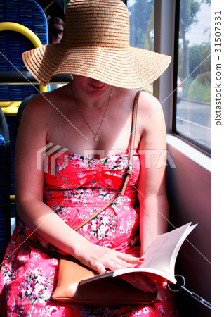 Woman in hat reading ebook on train bus 31507331