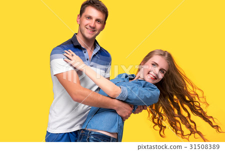 Portrait of a young couple standing against yellow Portrait of a young couple standing against yellow 31508389
