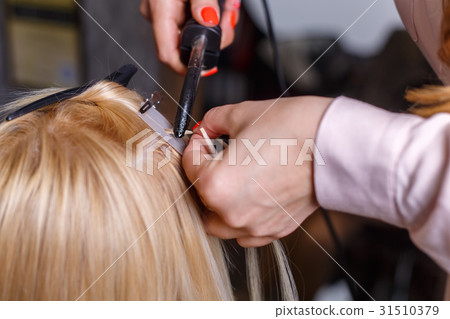 Hair extensions procedure. Hairdresser does hair Hair extensions procedure. Hairdresser does hair 31510379